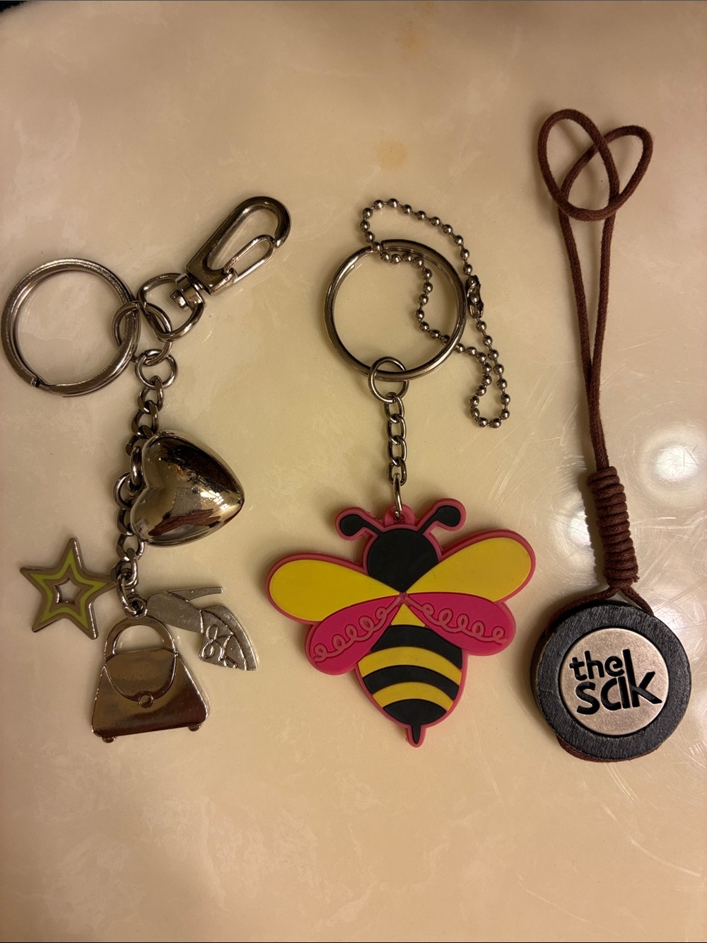 Set of 3 charms : Lily Bloom Silicon keychain
The Sak Logo & Metal Charms